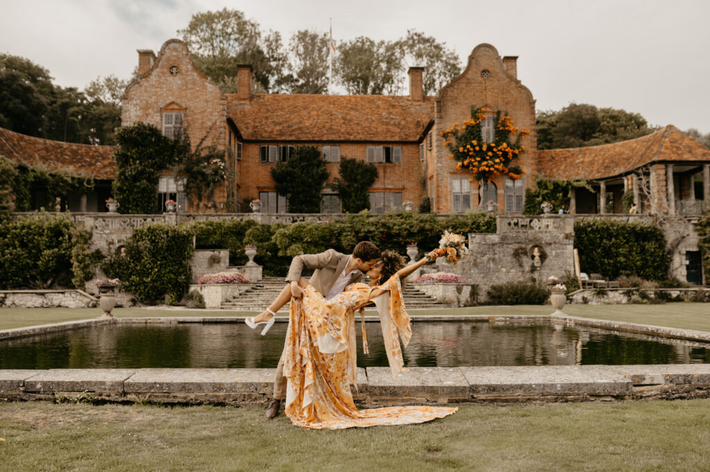 A couple who have just got married at Port Lympne Safari park in Kent kiss and celebrate in front of the manor house 