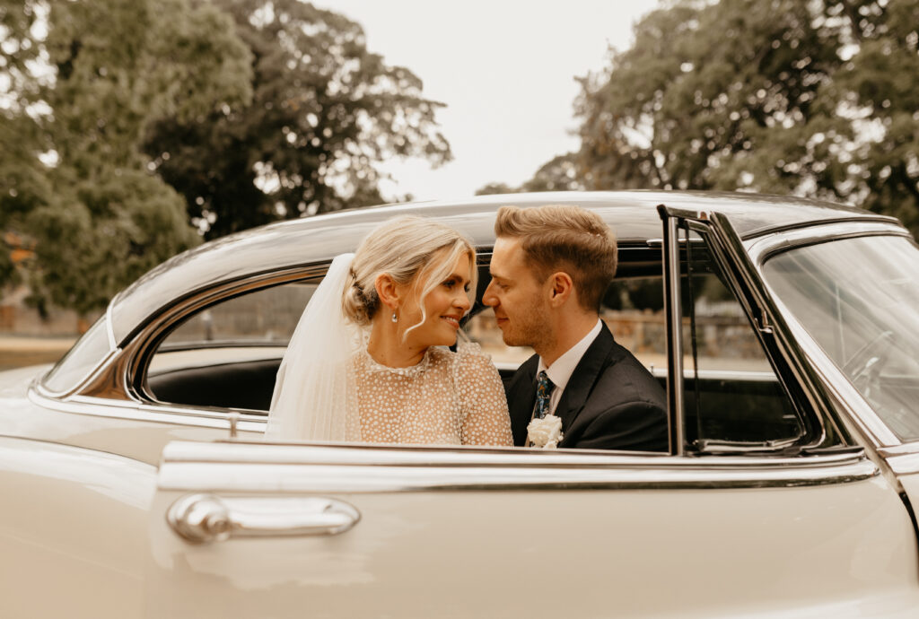 A couple who have just got married at Hatfield House in Hatfield celebrate their love by taking a drive in their new classic wedding car
