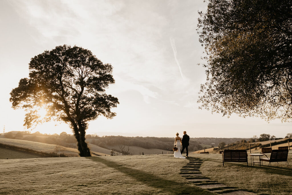 Best Surrey wedding venues. A newly married couple walking in the grounds of Botley Hill Barn