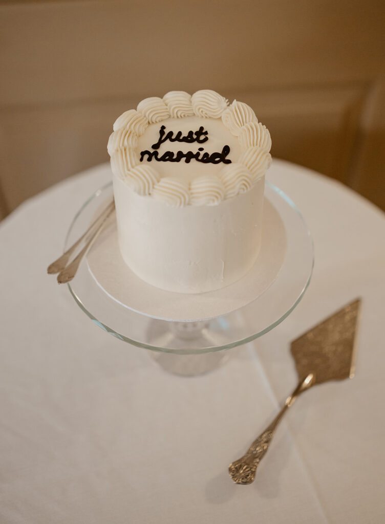 A just married wedding cake that's white with black writing