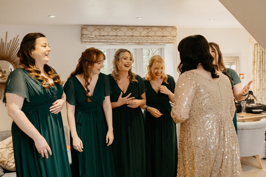 Bridesmaids reacting to the bride wearing a sparkly gold wedding dress