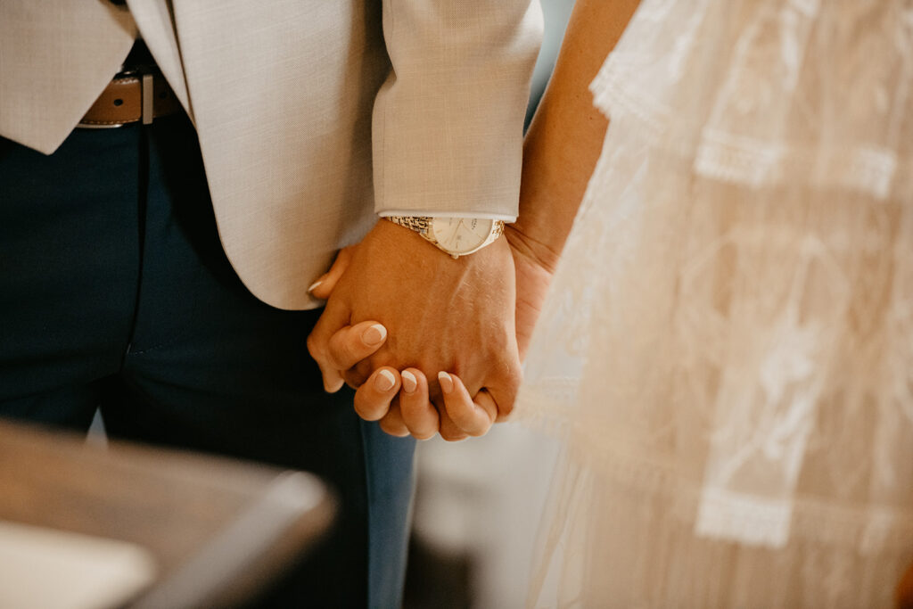 A couple holding hands in their wedding ceremony