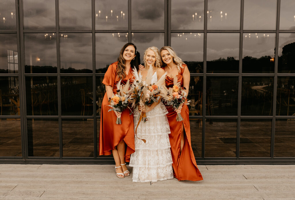 A bride and bridesmaids wearing orange autumnal dresses