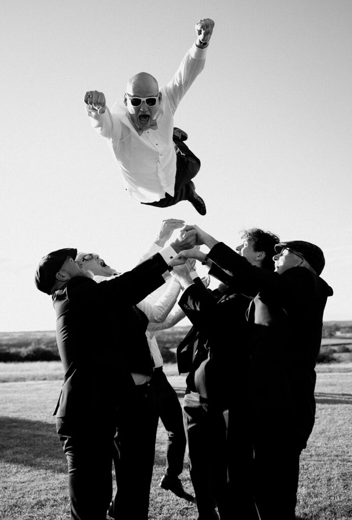 Fun photo of a groom being thrown into the air by his groomsmen